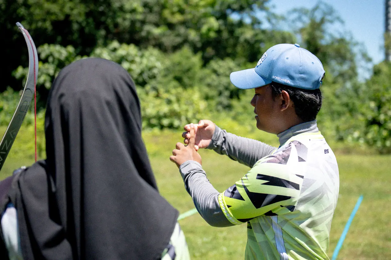 A Boltz coach standing beside a student on the field, setting her hands on the bow