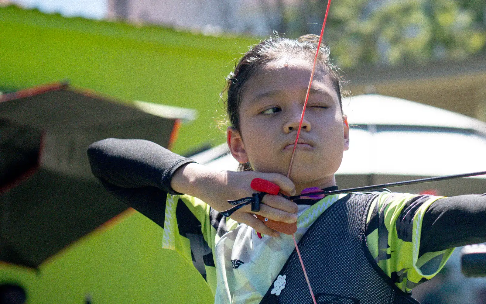 A Boltz archer at full draw, sighting down the arrow, mid-competition